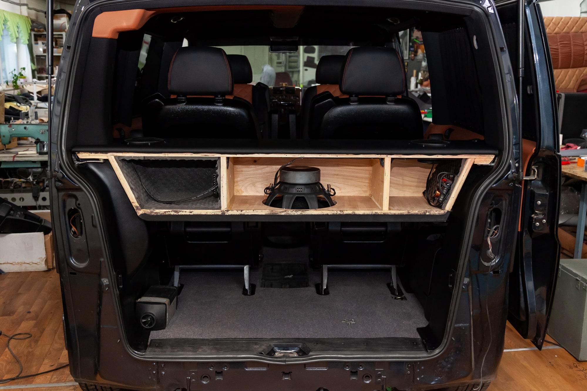 A box made of wood and sawn holes with black leather for the installation of subwoofers and speakers for an audio system with a loud sound and bass in van car trunk.