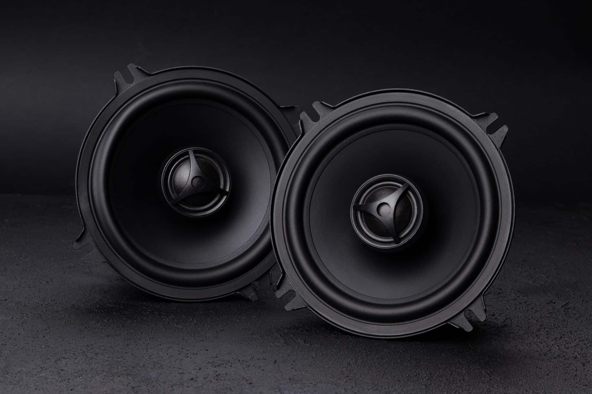 A pair of car audio speakers on a dark background.
